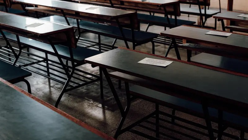 Rows of empty wooden desks in a classroom, the kind where the firearms safety course is taught
